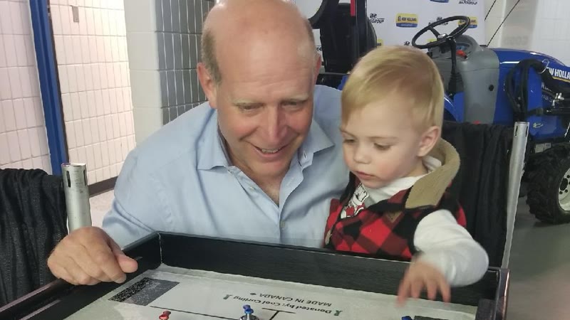 A man and a young child playing on a Cool Curling table